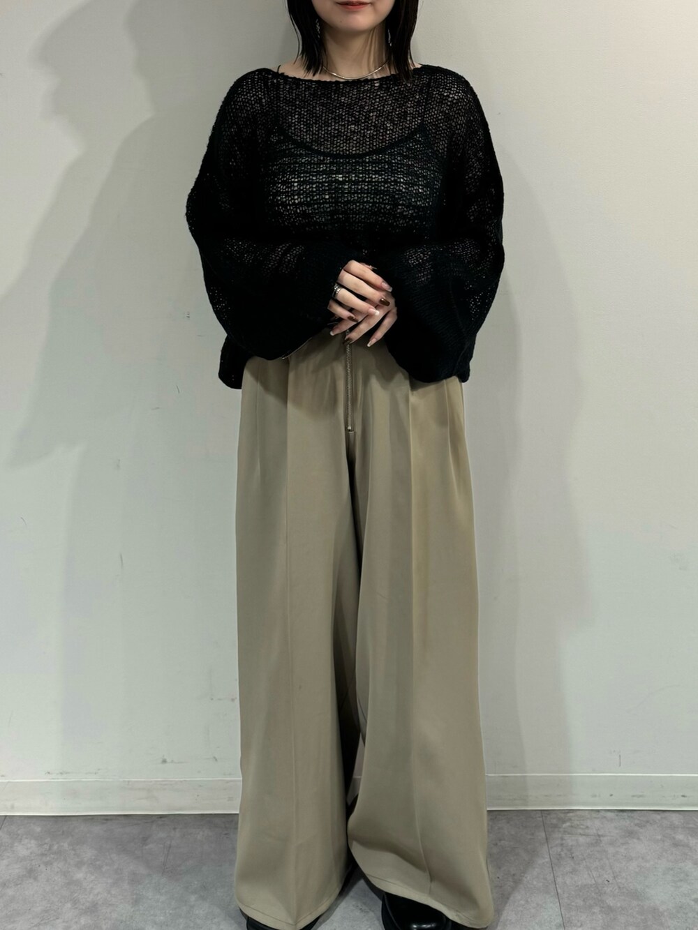 ベージュ系のスラックス、ブラック系のニット/セーターを着用したレディースの秋コーディネートの2枚目の写真