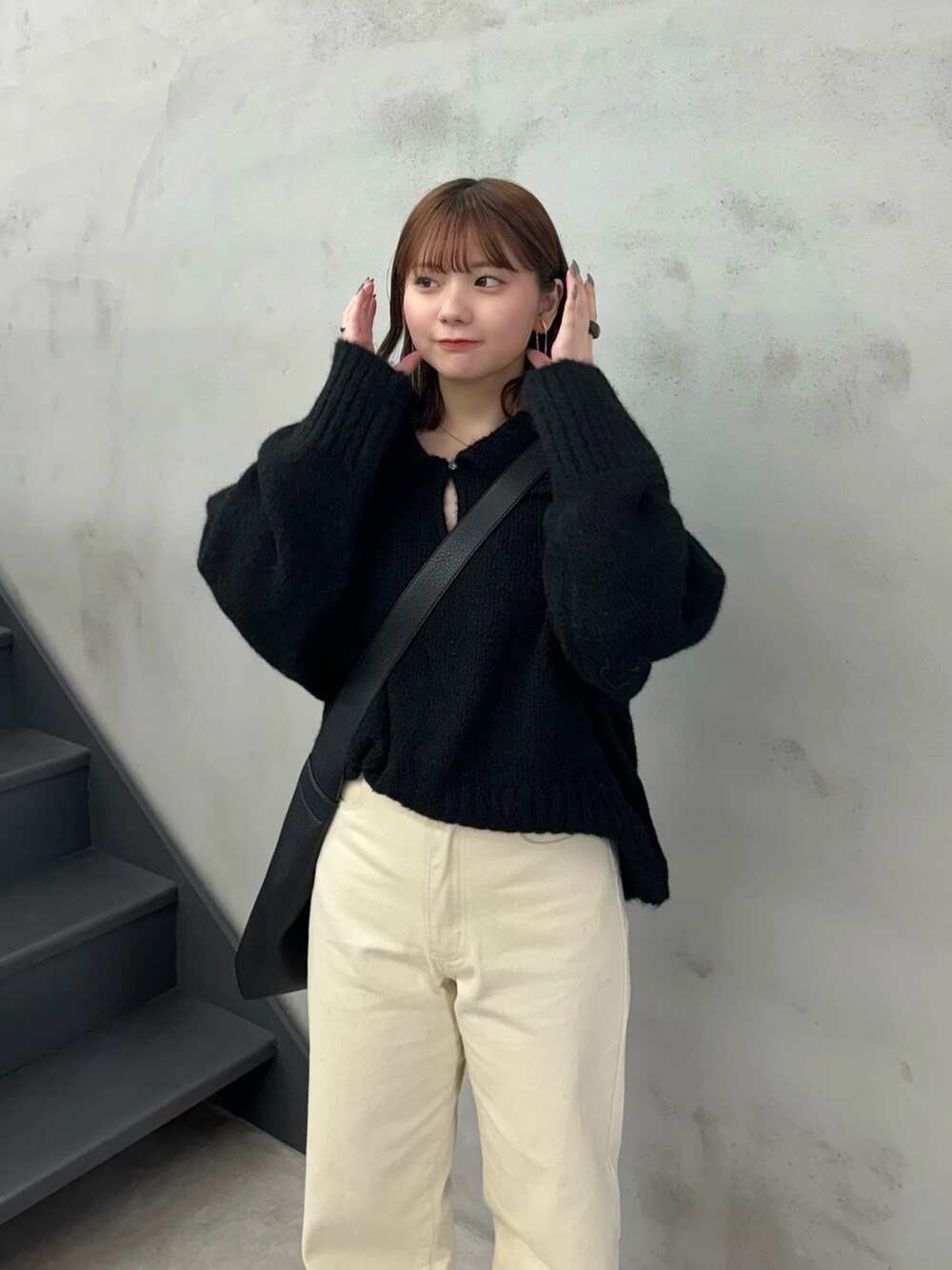 ブラック系のニット/セーター、ベージュ系のデニムパンツ、ブラック系のショルダーバッグを着用したレディースの冬コーディネートの5枚目の写真