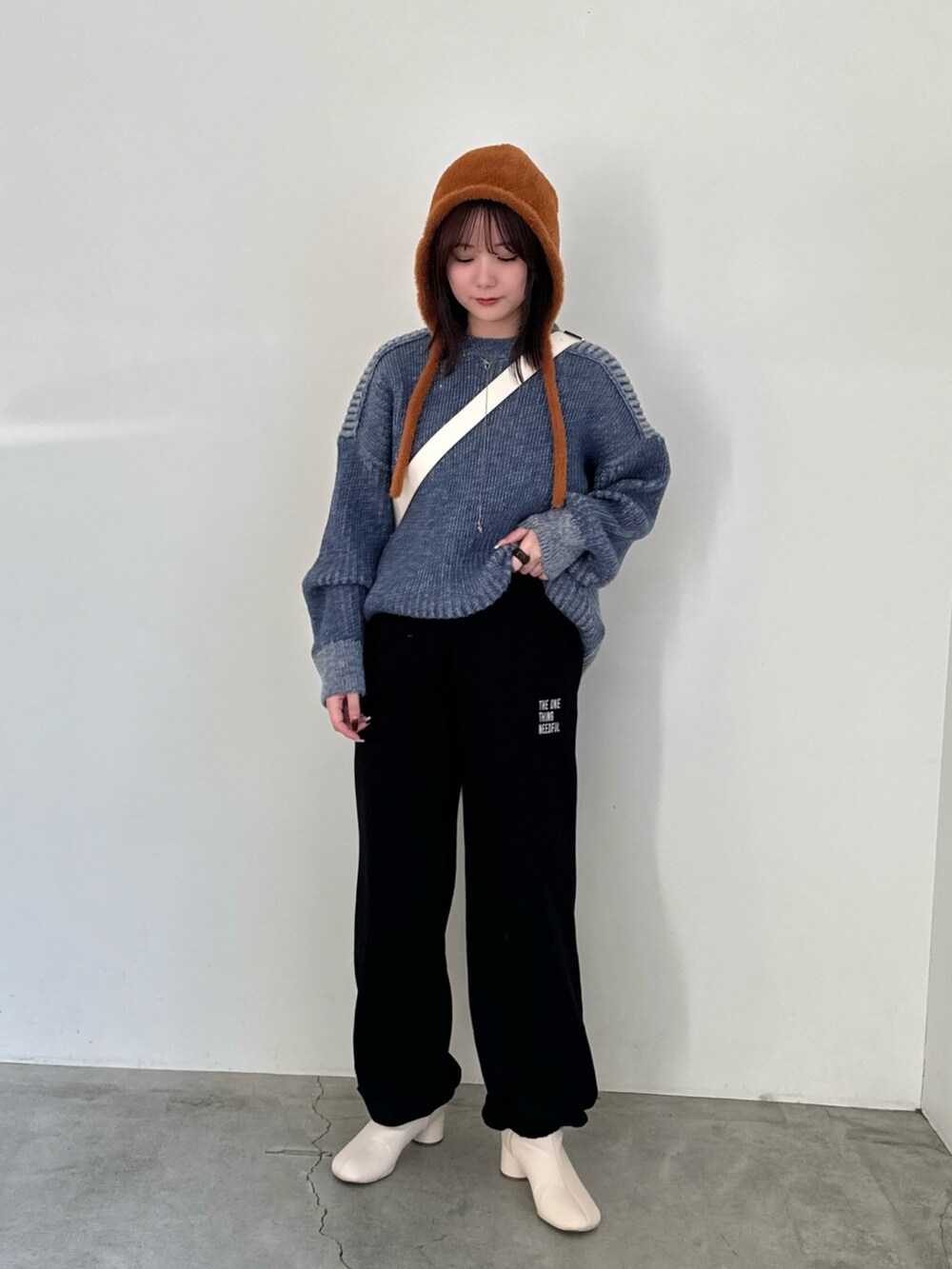 ブラック系のスウェットパンツ、ブルー系のニット/セーター、ホワイト系のショルダーバッグを着用したレディースの秋コーディネートの5枚目の写真