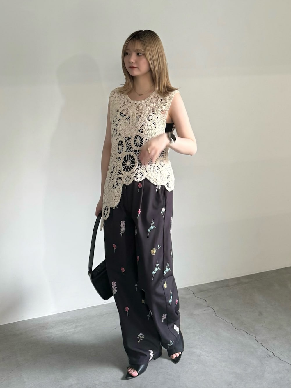 ホワイト系のベスト、ブラック系のキャミソール、ブラック系のショルダーバッグを着用したレディースの春コーディネートの2枚目の写真