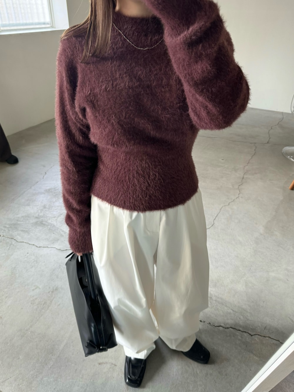 ブラウン系のニット/セーター、ホワイト系のその他パンツ、ブラック系のハンドバッグを着用したレディースの秋コーディネートの4枚目の写真
