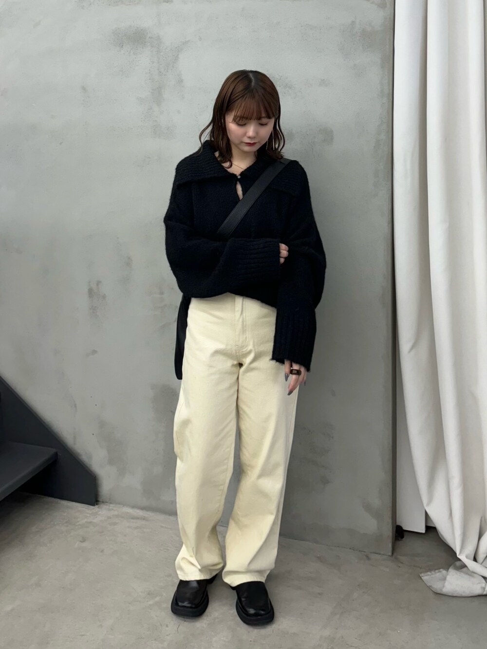 ブラック系のニット/セーター、ベージュ系のデニムパンツ、ブラック系のショルダーバッグを着用したレディースの冬コーディネートの3枚目の写真
