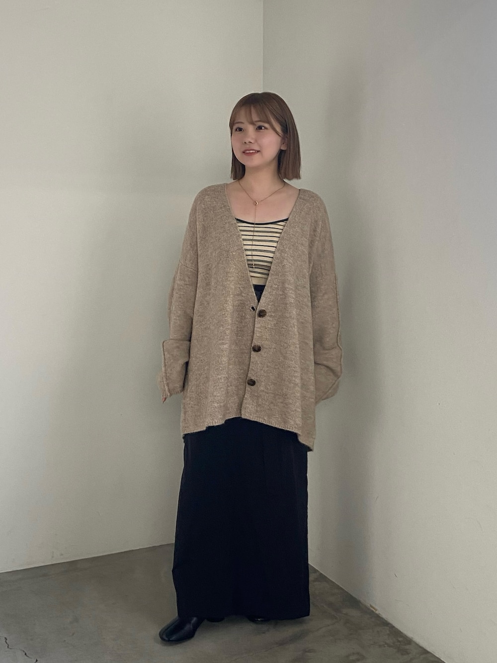 ベージュ系のカーディガン/ボレロ、ブラック系のスカートを着用したレディースの夏コーディネートの2枚目の写真
