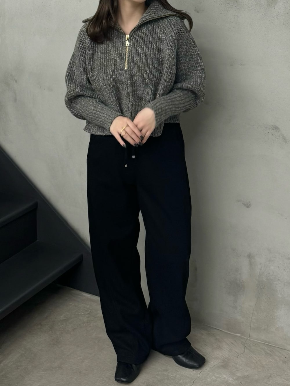 グレー系のニット/セーター、ブラック系のスウェットパンツを着用したレディースの秋コーディネートの2枚目の写真