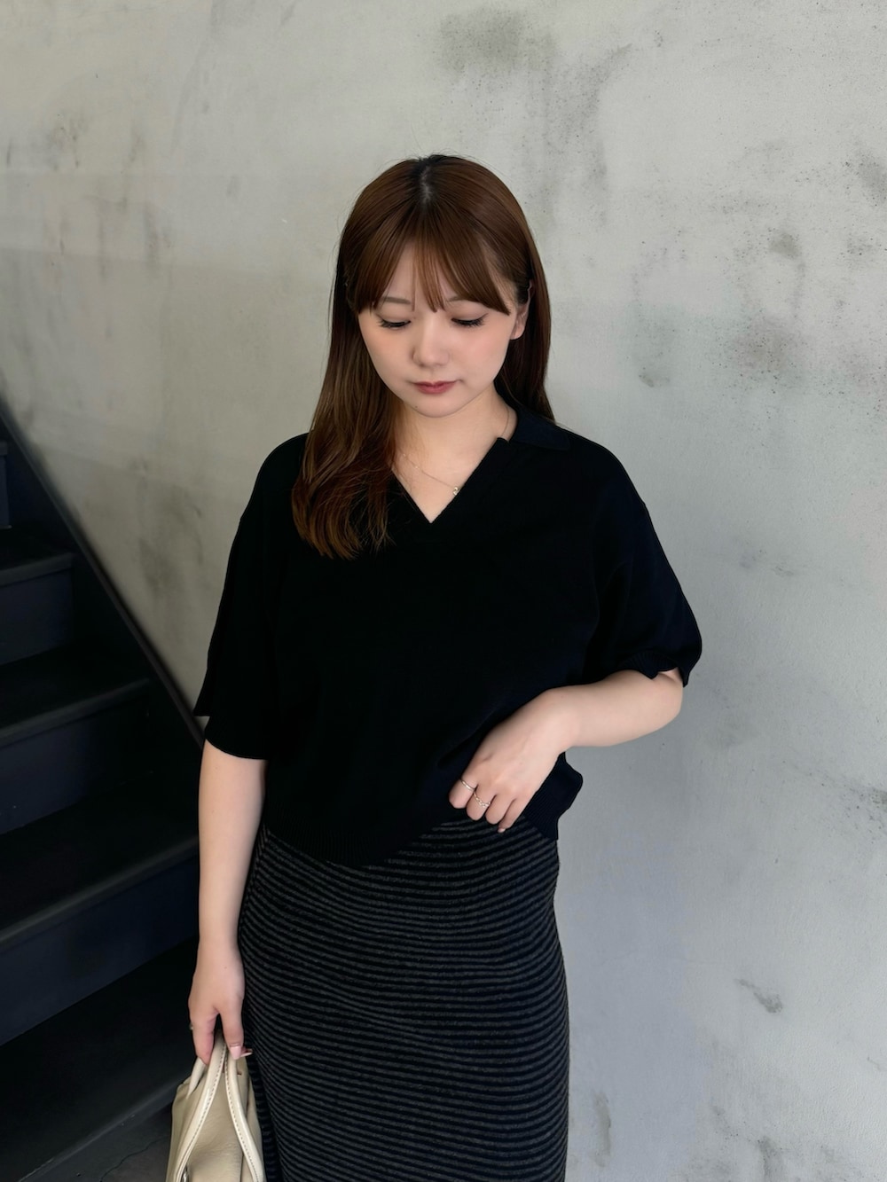 ブラック系のニット/セーター、ブラック系のスカート、ベージュ系のボストンバッグを着用したレディースの夏コーディネートの3枚目の写真