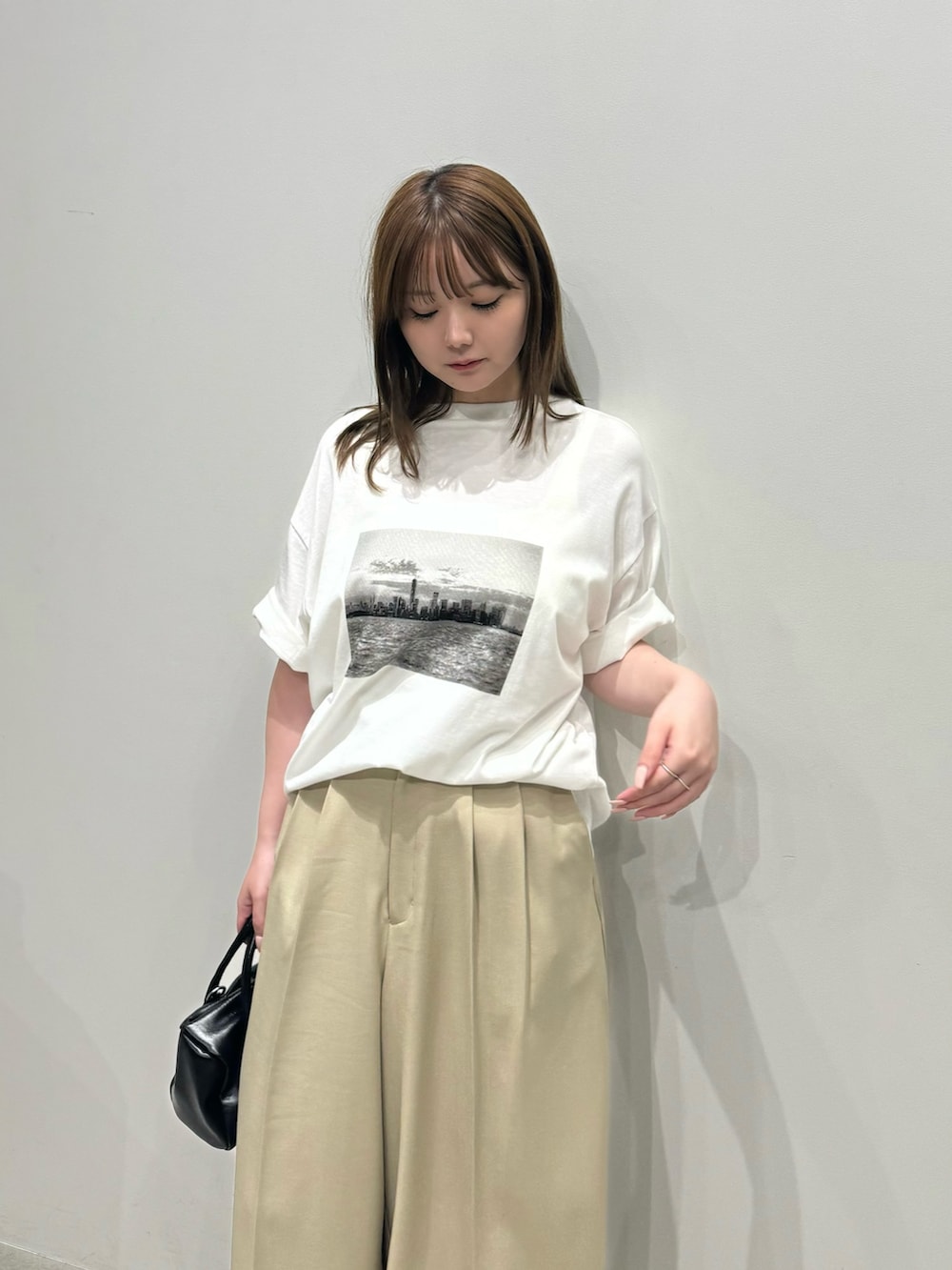 ホワイト系のTシャツ/カットソー、ベージュ系のスラックス、ブラック系のボストンバッグを着用したレディースの夏コーディネートの3枚目の写真