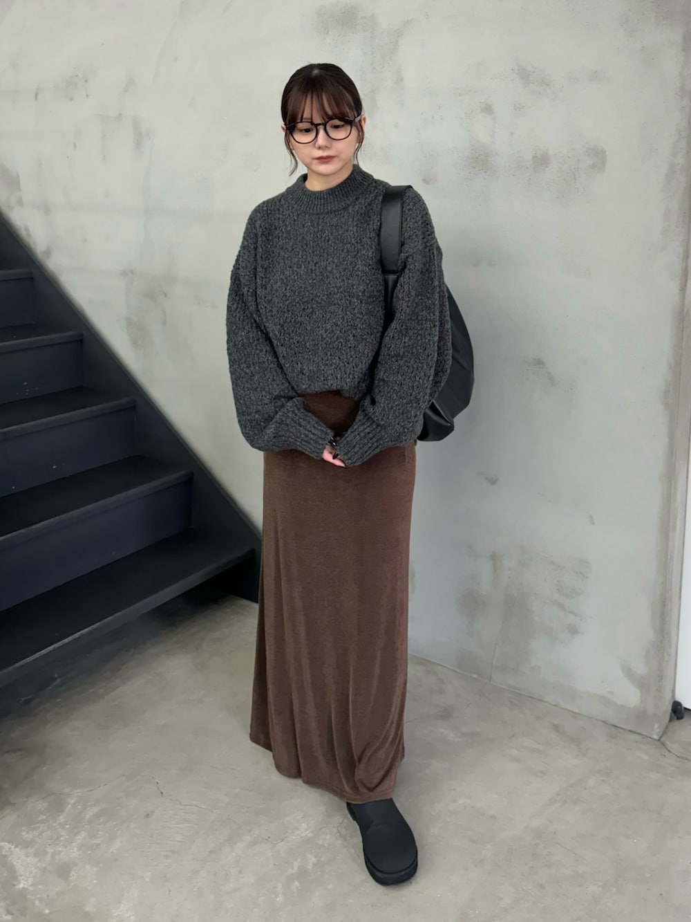 グレー系のニット/セーター、ブラウン系のスカート、ブラック系のスリッポンを着用したレディースの冬コーディネートの2枚目の写真