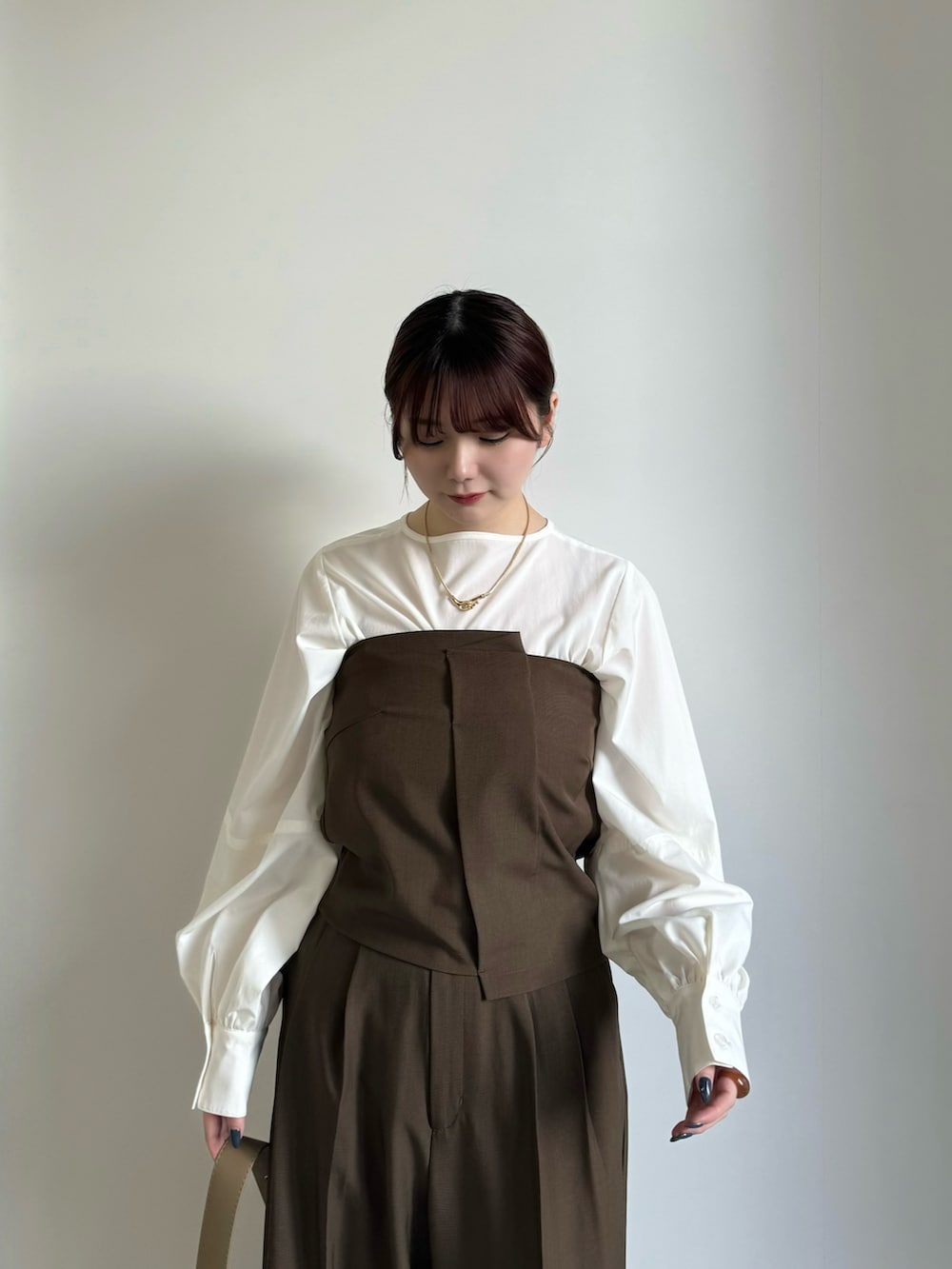 ブラウン系のスラックス、ホワイト系のシャツ/ブラウス、ブラウン系のチューブトップを着用したレディースの冬コーディネートの4枚目の写真