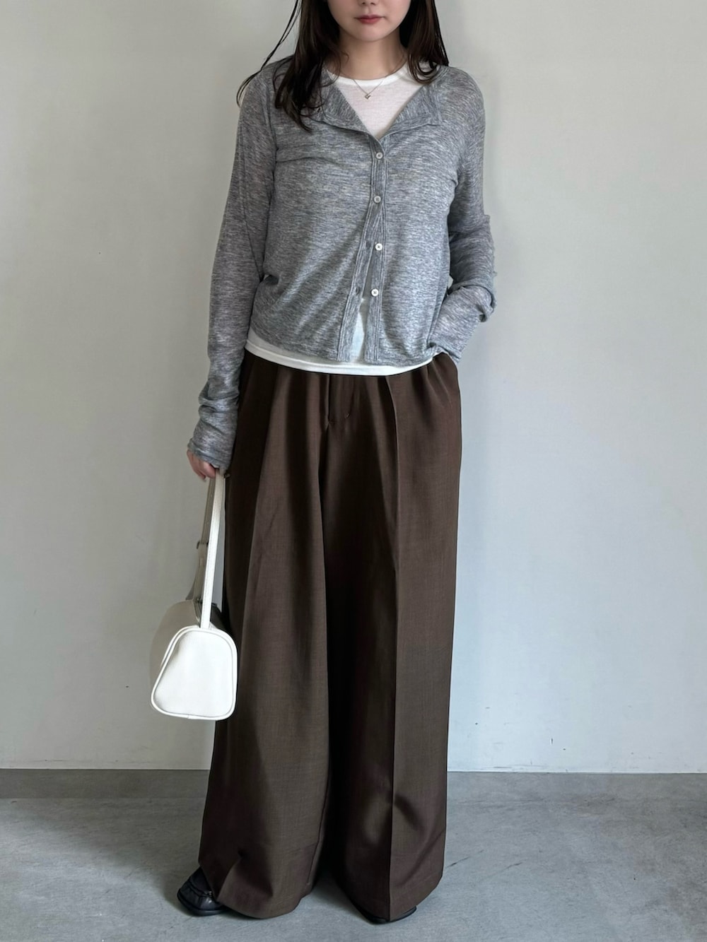 グレー系のカーディガン/ボレロ、ブラウン系のスラックス、ホワイト系のハンドバッグを着用したレディースの春コーディネートの3枚目の写真