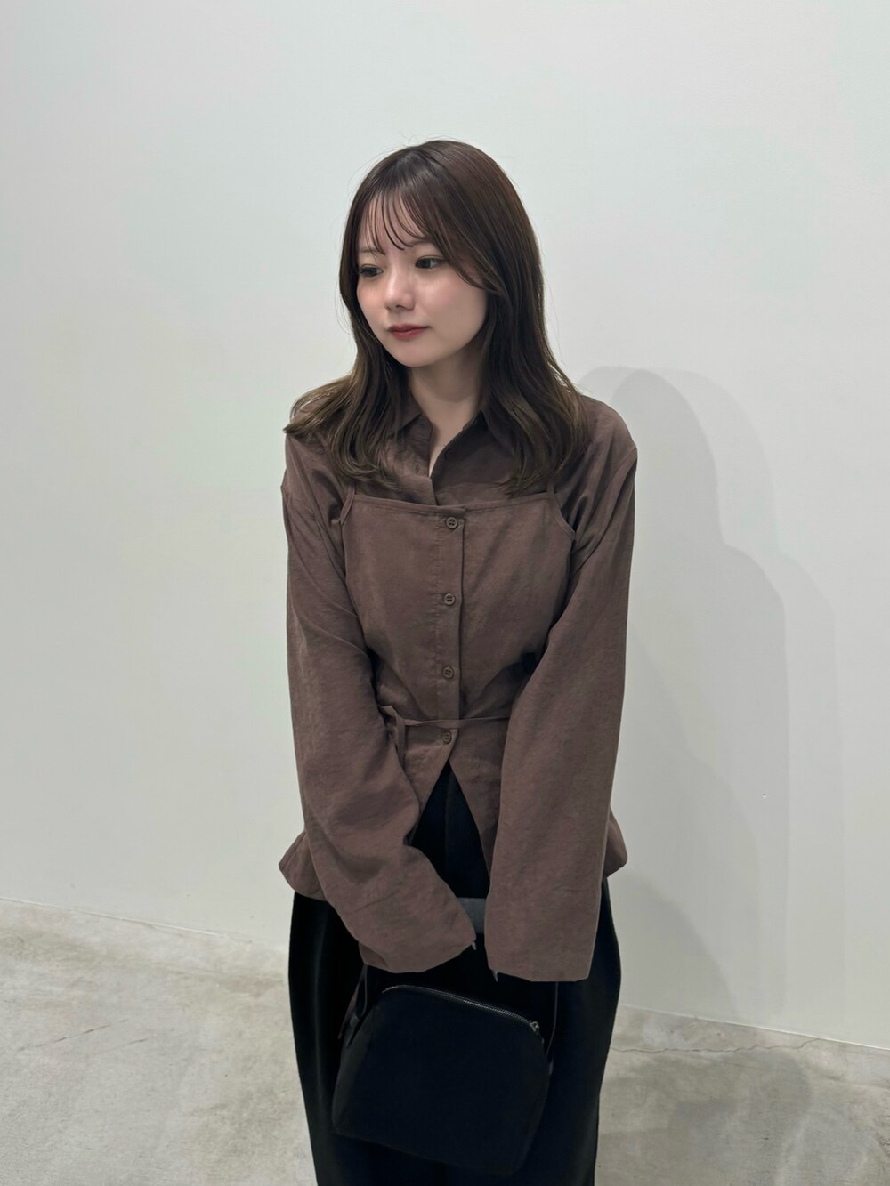 ブラック系のスラックス、ブラック系のハンドバッグ、ブラック系のブーツを着用したレディースの秋コーディネートの4枚目の写真