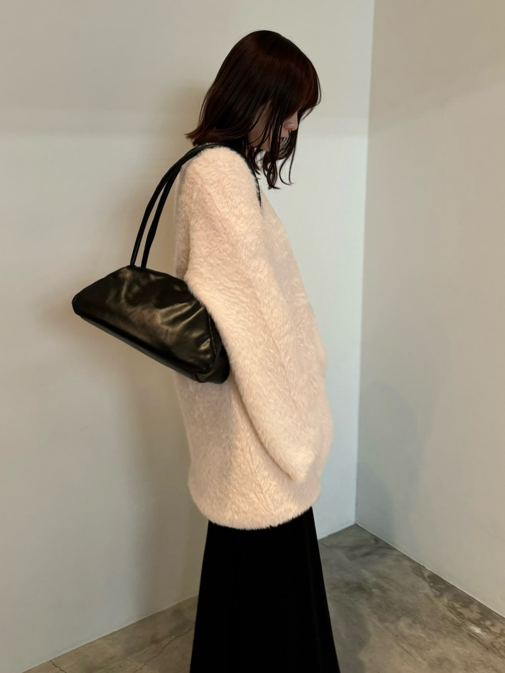 ピンク系のニット/セーター、ブラック系のスカート、ブラック系のスリッポンを着用したレディースの冬コーディネートの2枚目の写真