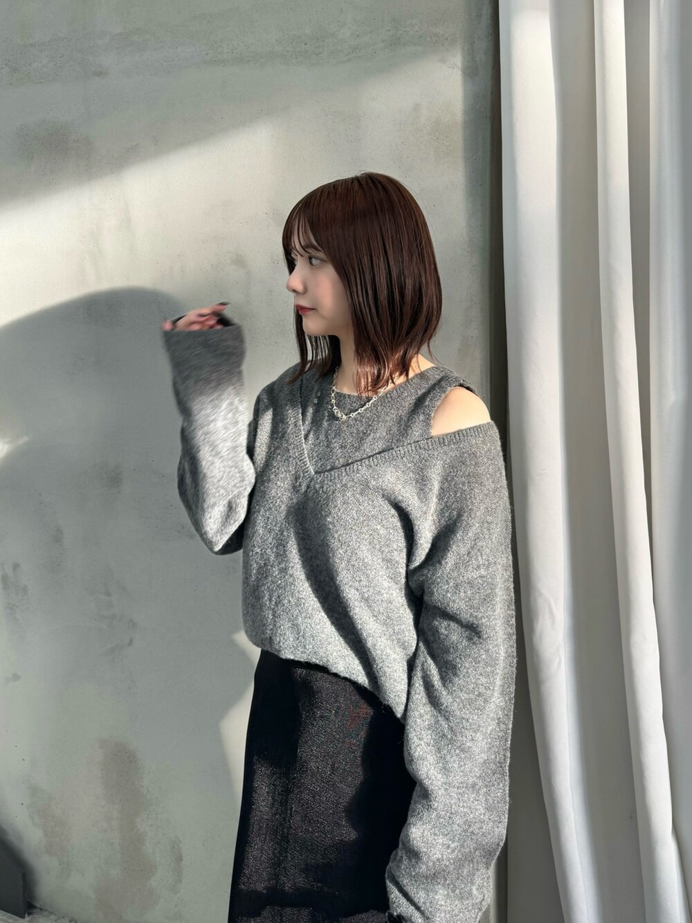 グレー系のニット/セーター、ブラック系のスカート、ブラック系のハンドバッグを着用したレディースの秋コーディネートの4枚目の写真