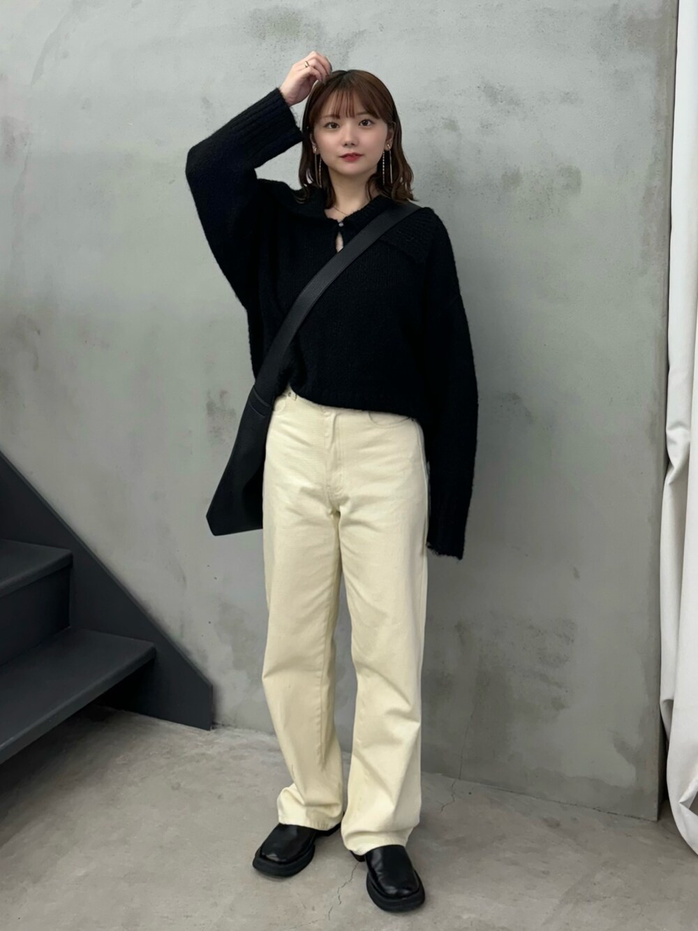 ブラック系のニット/セーター、ベージュ系のデニムパンツ、ブラック系のショルダーバッグを着用したレディースの冬コーディネートの2枚目の写真
