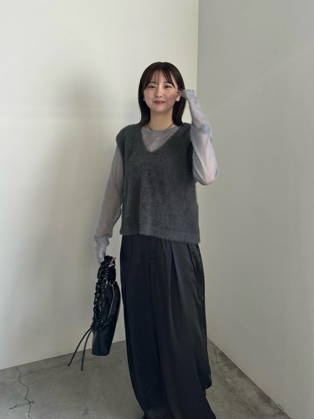 グレー系のベスト、グレー系のニット/セーター、ブラック系のスラックスを着用したレディースの秋コーディネートの3枚目の写真