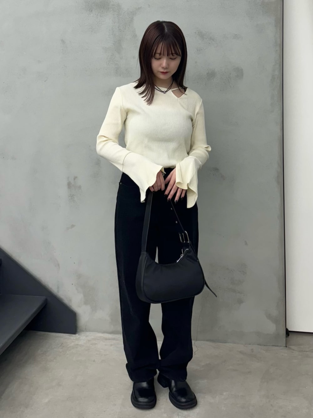 ブラック系のデニムパンツ、ブラック系のショルダーバッグ、ホワイト系のTシャツ/カットソーを着用したレディースの冬コーディネートの2枚目の写真