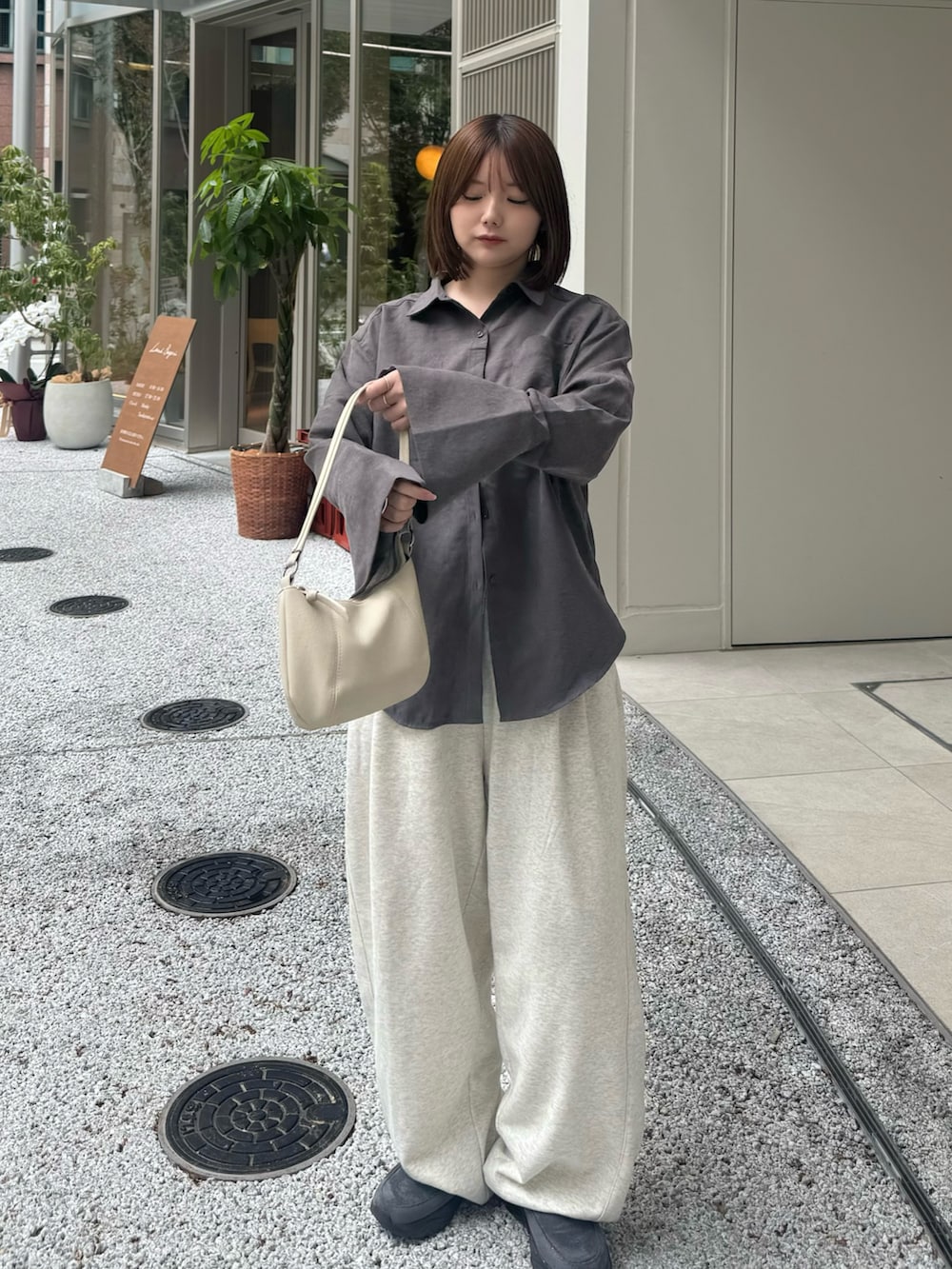 グレー系のシャツ/ブラウス、ベージュ系のスウェットパンツ、ホワイト系のハンドバッグを着用したレディースの秋コーディネートの2枚目の写真