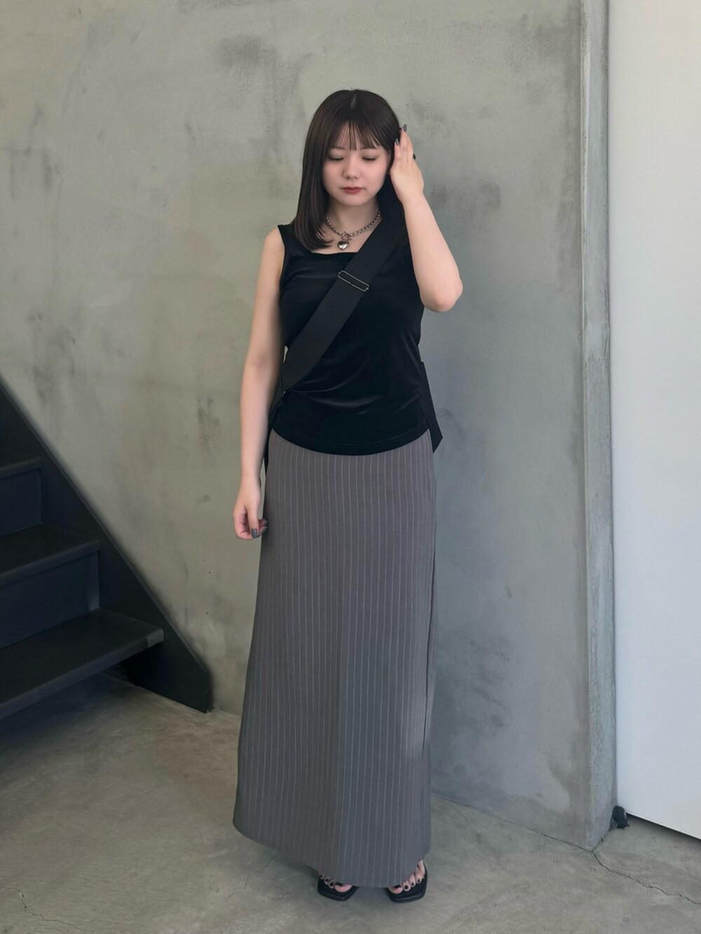 グレー系のスカート、ブラック系のショルダーバッグ、ブラック系のタンクトップを着用したレディースの夏コーディネートの2枚目の写真