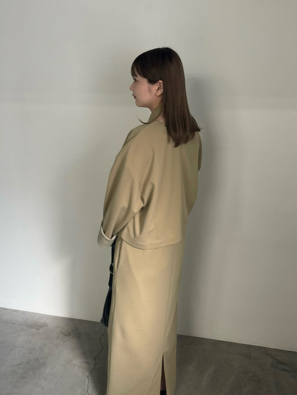 ベージュ系のセットアップ、ブラック系のハンドバッグ、ブラック系のスリッポンを着用したレディースの夏コーディネートの3枚目の写真