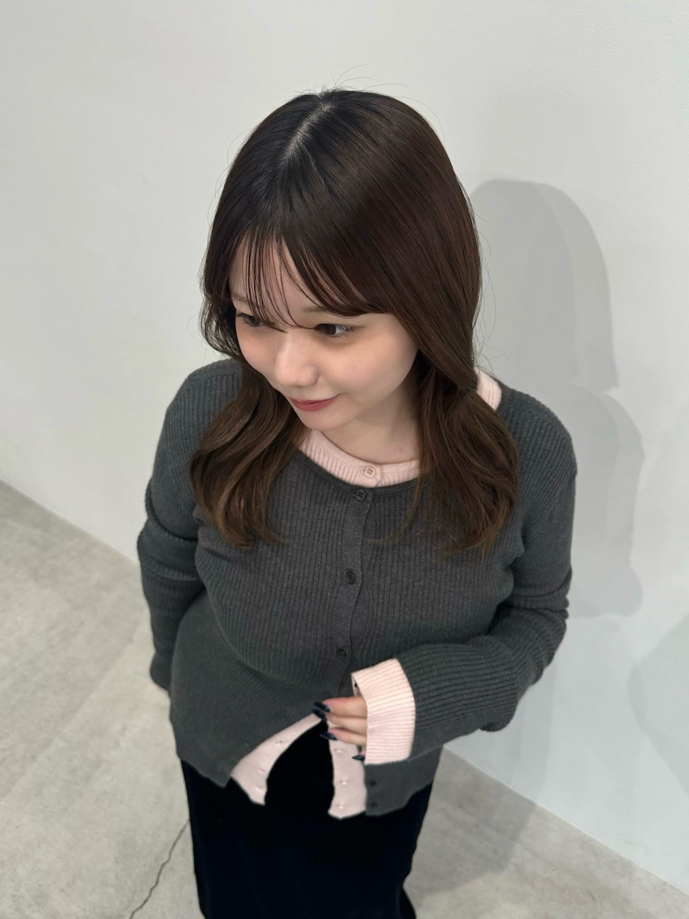 グレー系のカーディガン/ボレロ、ピンク系のカーディガン/ボレロ、ブラック系のスカートを着用したレディースの冬コーディネートの6枚目の写真