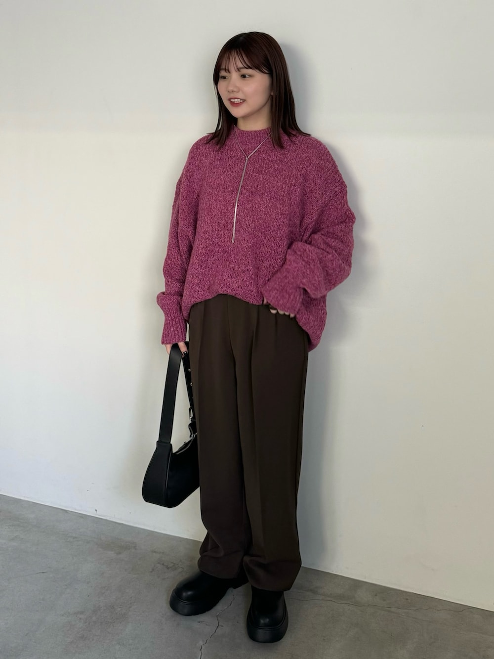 ブラウン系のスラックス、ピンク系のニット/セーター、ブラック系のブーツを着用したレディースの冬コーディネートの2枚目の写真