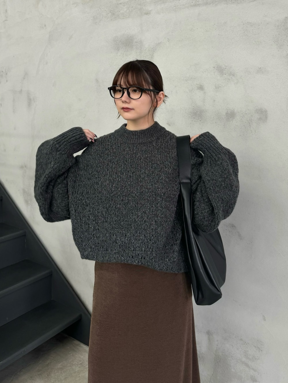 グレー系のニット/セーター、ブラウン系のスカート、ブラック系のスリッポンを着用したレディースの冬コーディネートの4枚目の写真