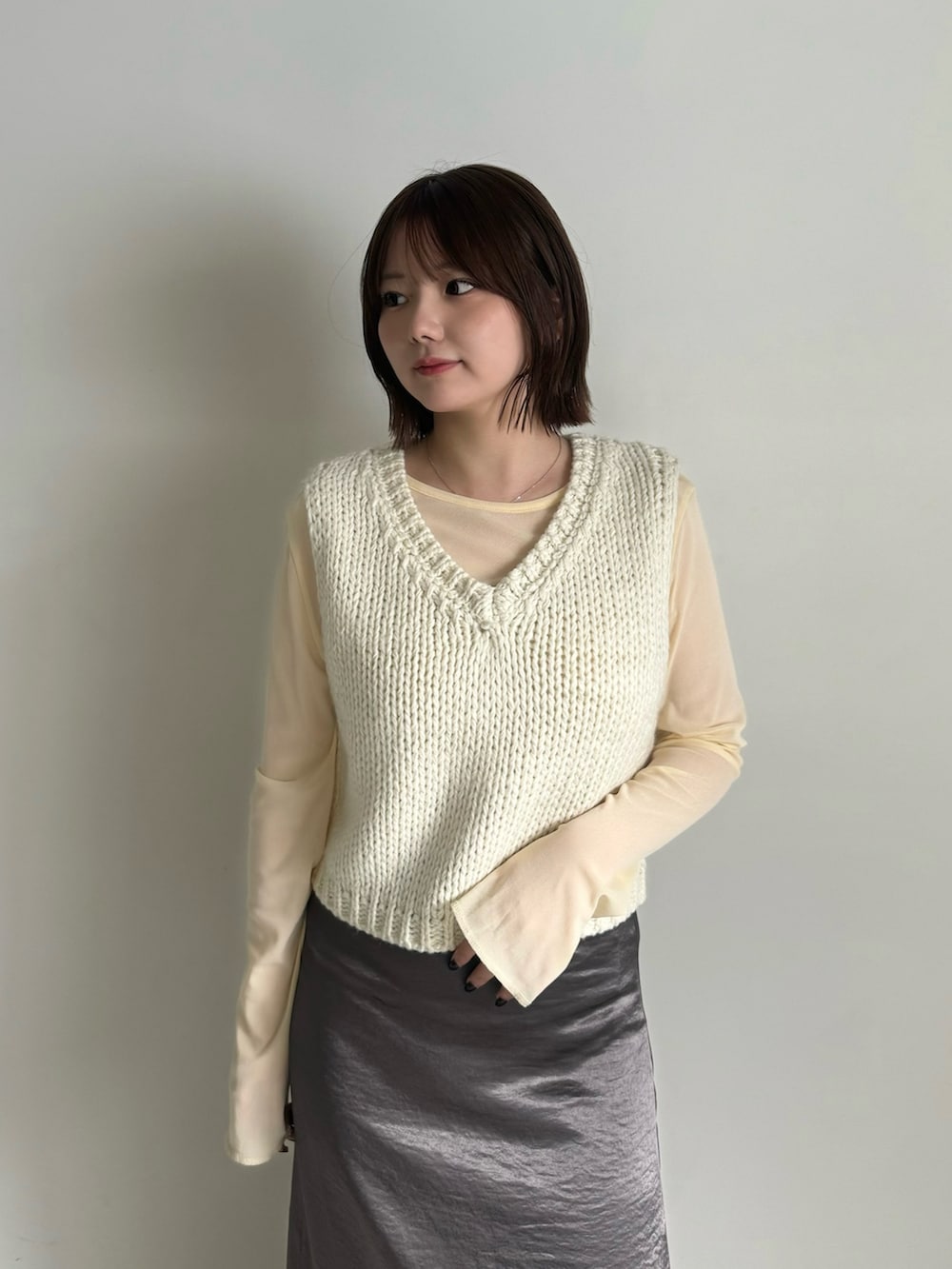 ホワイト系のベスト、ベージュ系のTシャツ/カットソー、グレー系のスカートを着用したレディースの秋コーディネートの3枚目の写真