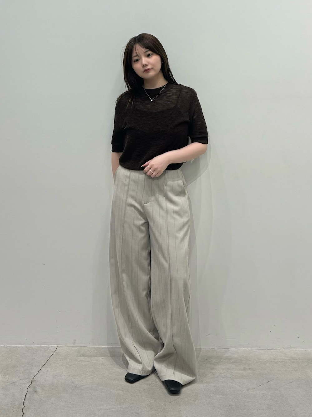 ブラウン系のニット/セーター、グレー系のスラックス、ブラック系のスリッポンを着用したレディースの春コーディネートの3枚目の写真