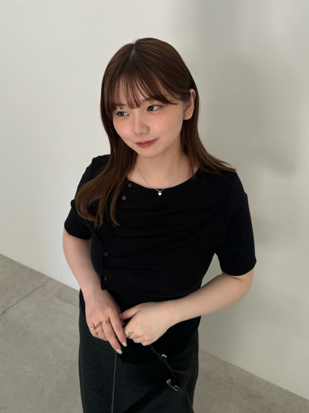ブラック系のTシャツ/カットソー、ブラック系のハンドバッグ、ブラック系のスカートを着用したレディースの夏コーディネートの4枚目の写真