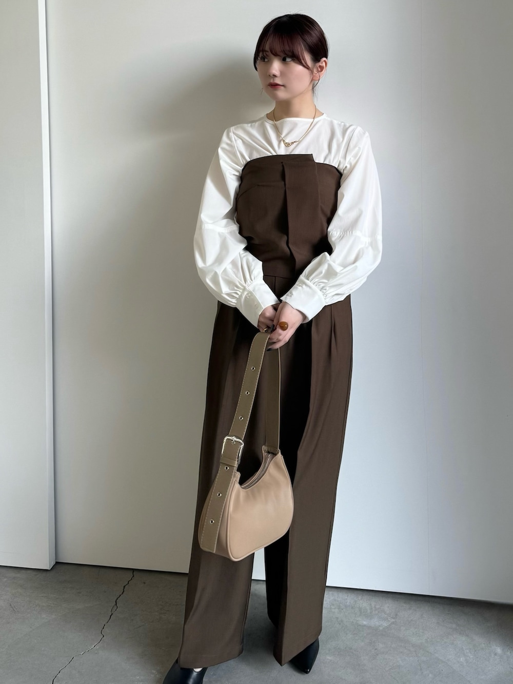 ブラウン系のスラックス、ホワイト系のシャツ/ブラウス、ブラウン系のチューブトップを着用したレディースの冬コーディネートの2枚目の写真