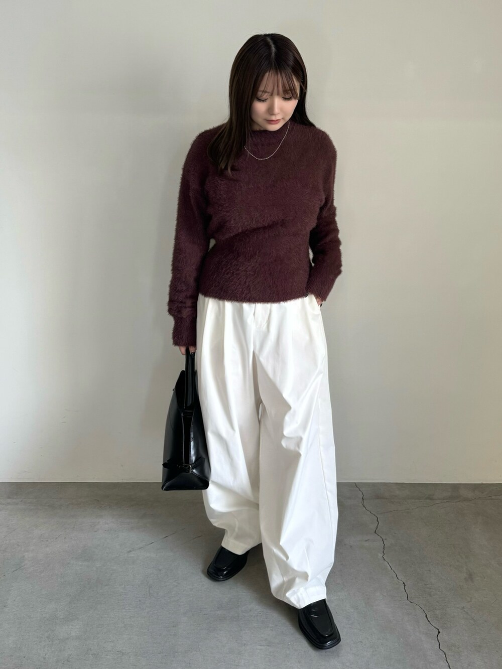 ブラウン系のニット/セーター、ホワイト系のその他パンツ、ブラック系のハンドバッグを着用したレディースの秋コーディネートの2枚目の写真