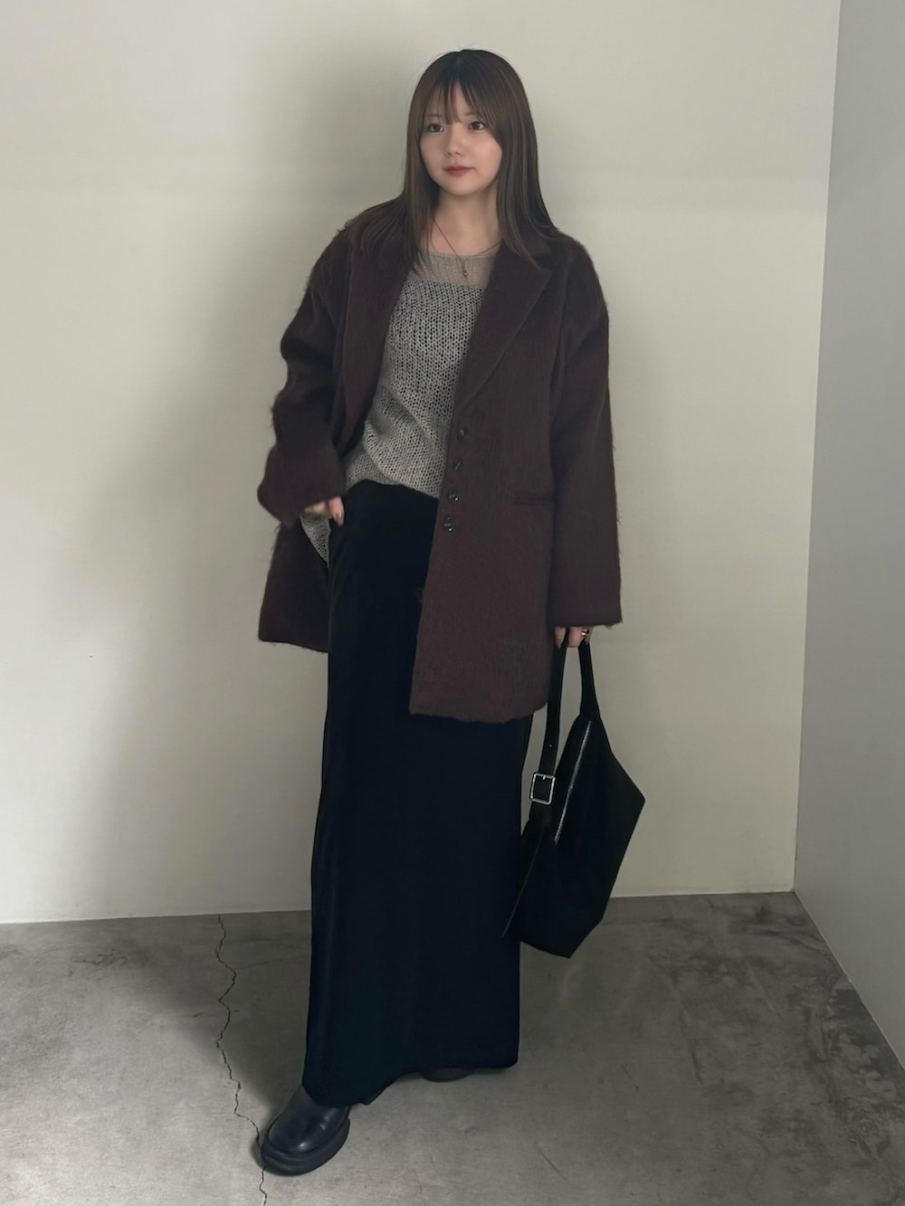 ブラウン系のテーラードジャケット、グレー系のニット/セーター、ブラック系のスカートを着用したレディースの秋コーディネートの2枚目の写真