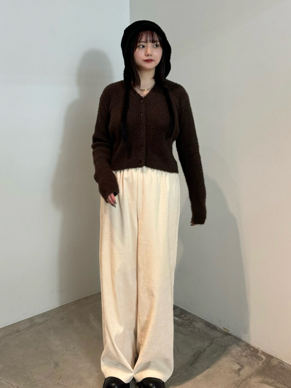 ブラウン系のカーディガン/ボレロ、ホワイト系のその他パンツ、ブラック系のブーツを着用したレディースの冬コーディネートの2枚目の写真