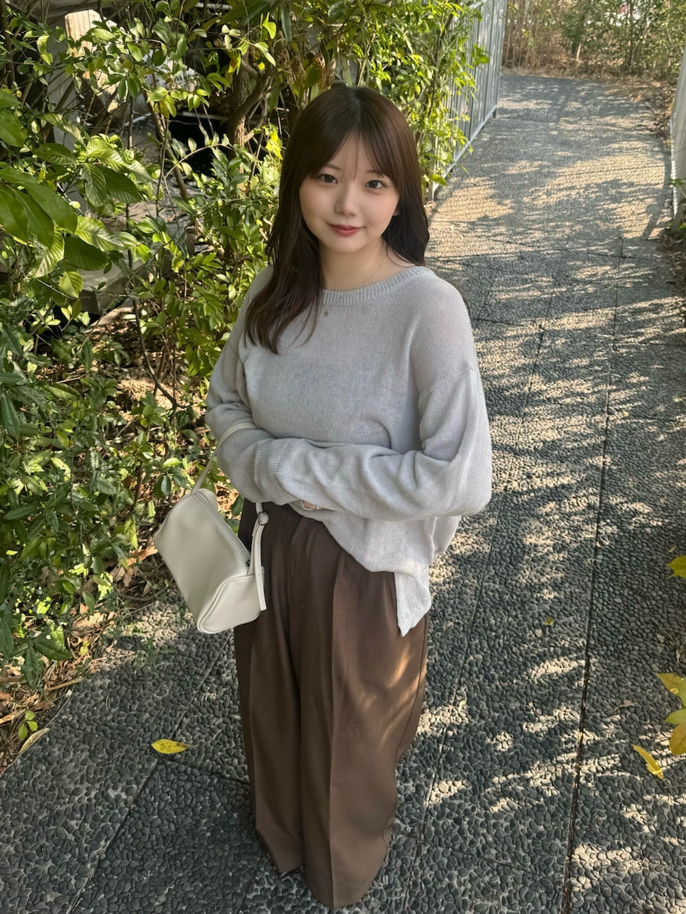 ブラック系のキャミソール、グレー系のニット/セーター、ブラウン系のスラックスを着用したレディースの春コーディネートの5枚目の写真