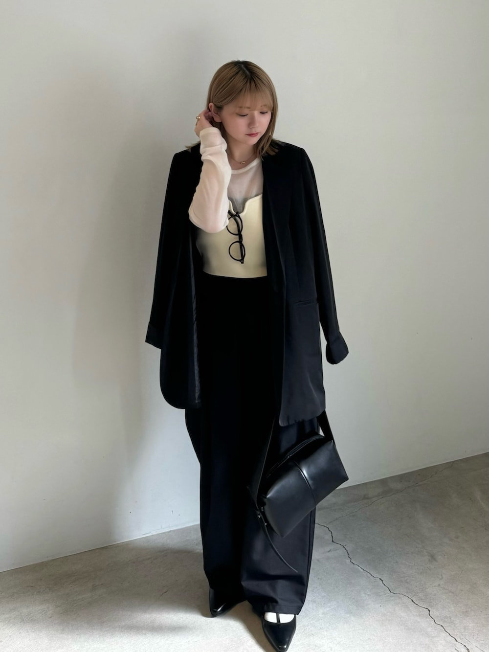 ブラック系のテーラードジャケット、ホワイト系のニット/セーター、ホワイト系のベストを着用したレディースの春コーディネートの2枚目の写真