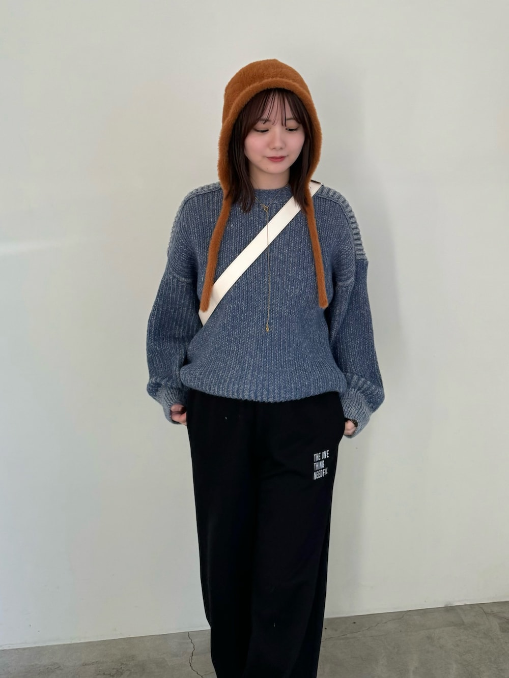 ブラック系のスウェットパンツ、ブルー系のニット/セーター、ホワイト系のショルダーバッグを着用したレディースの秋コーディネートの4枚目の写真