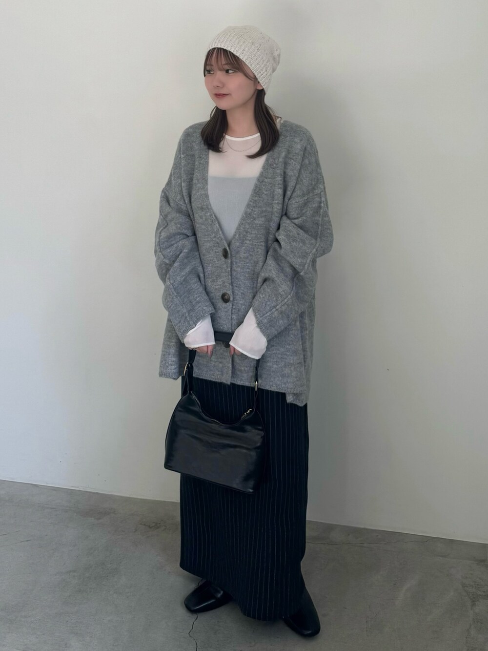 ベージュ系のカーディガン/ボレロ、ホワイト系のTシャツ/カットソー、ブルー系のスカートを着用したレディースの秋コーディネートの2枚目の写真