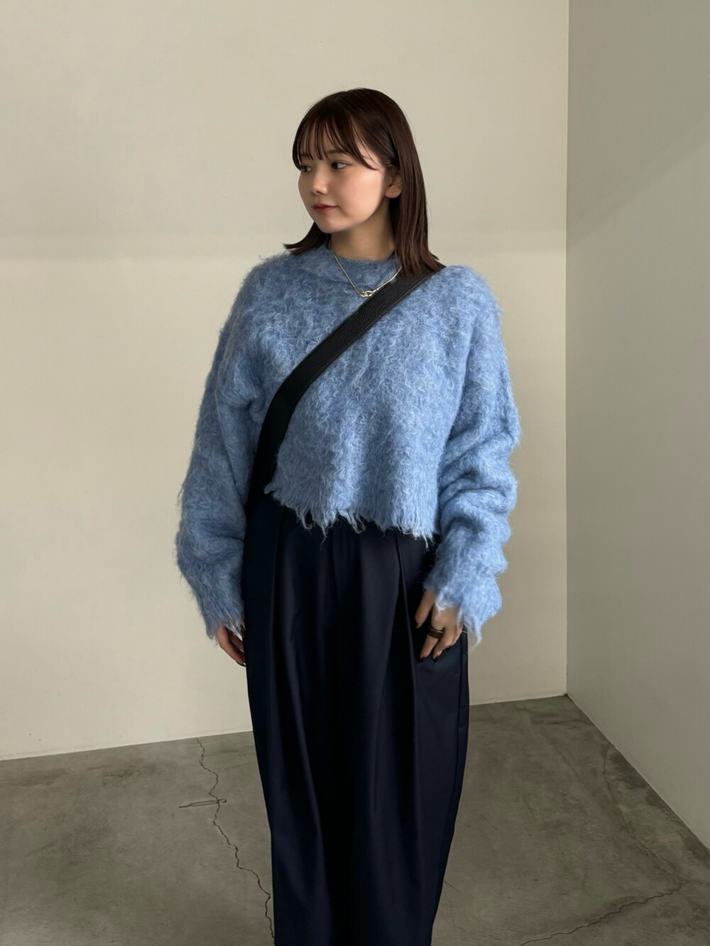 ブラック系のTシャツ/カットソー、ブルー系のニット/セーター、ブルー系のスラックスを着用したレディースの秋コーディネートの3枚目の写真