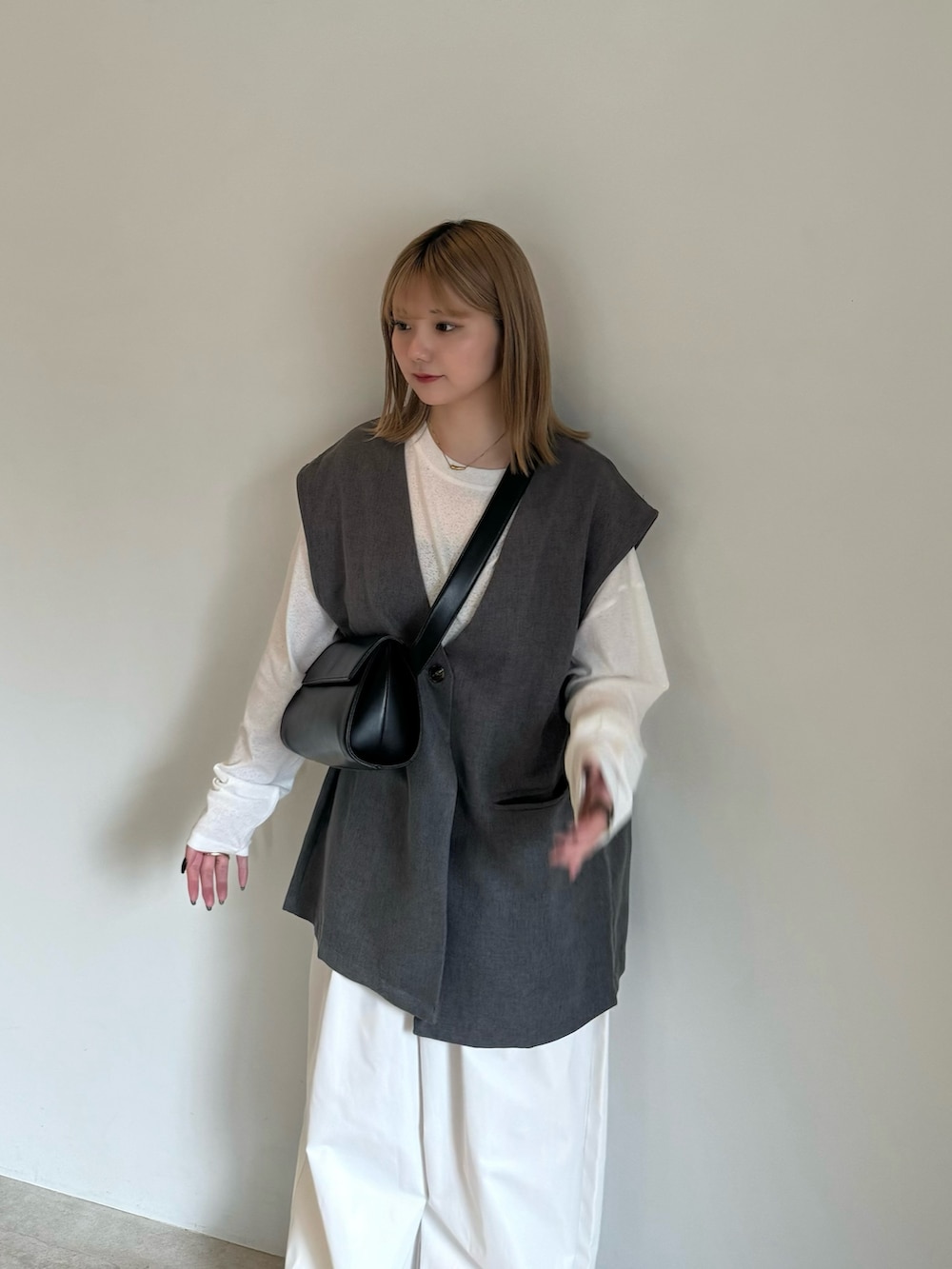 グレー系のベスト、ホワイト系のTシャツ/カットソー、ブラック系のキャミソールを着用したレディースの春コーディネートの4枚目の写真