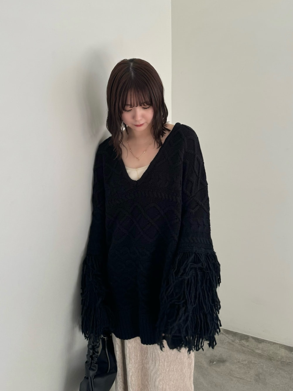 ブラック系のニット/セーター、ベージュ系のスカート、ブラック系のハンドバッグを着用したレディースの秋コーディネートの3枚目の写真