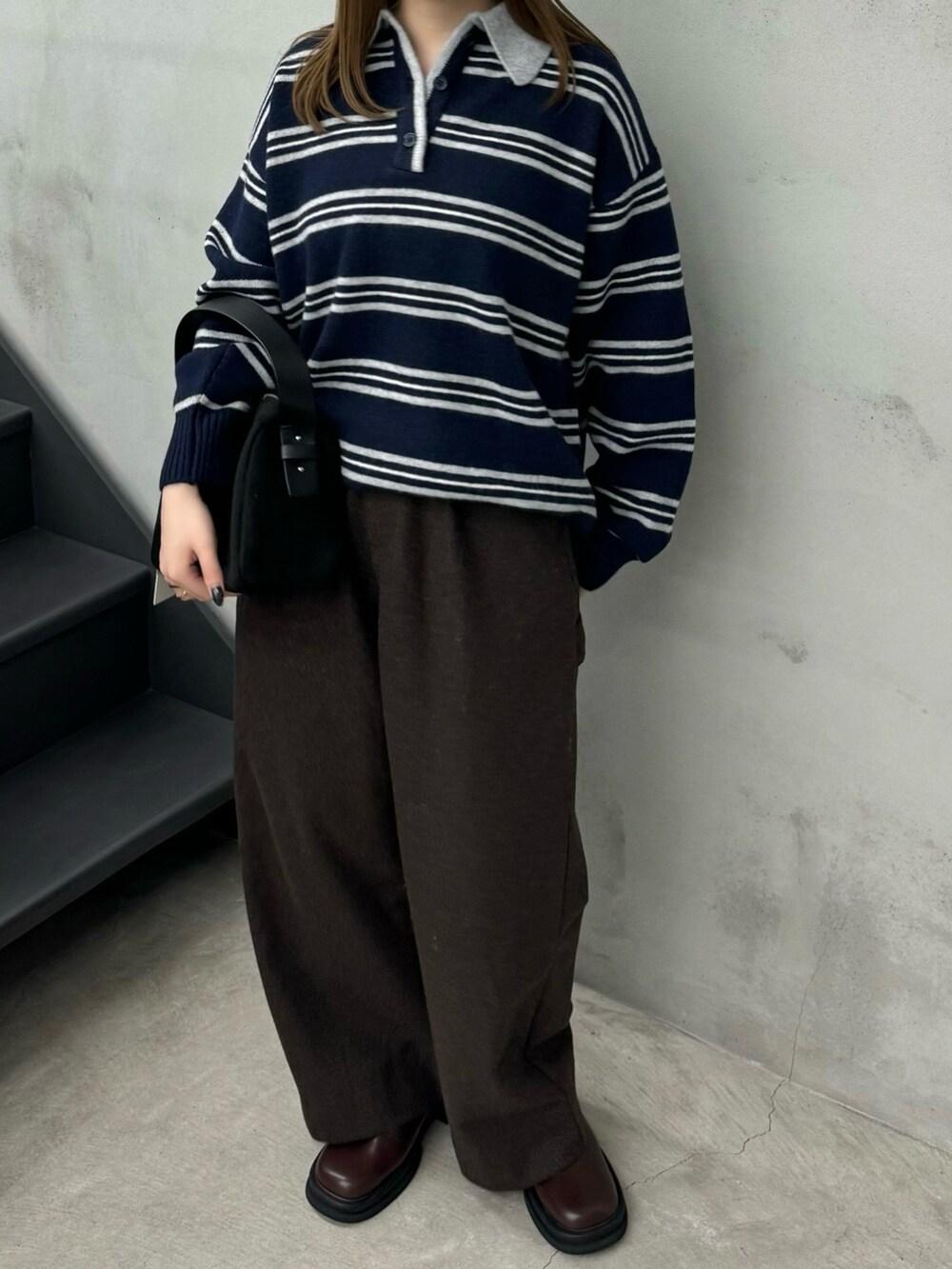 ブルー系のニット/セーター、ブラウン系のその他パンツ、ブラック系のハンドバッグを着用したレディースの秋コーディネートの2枚目の写真