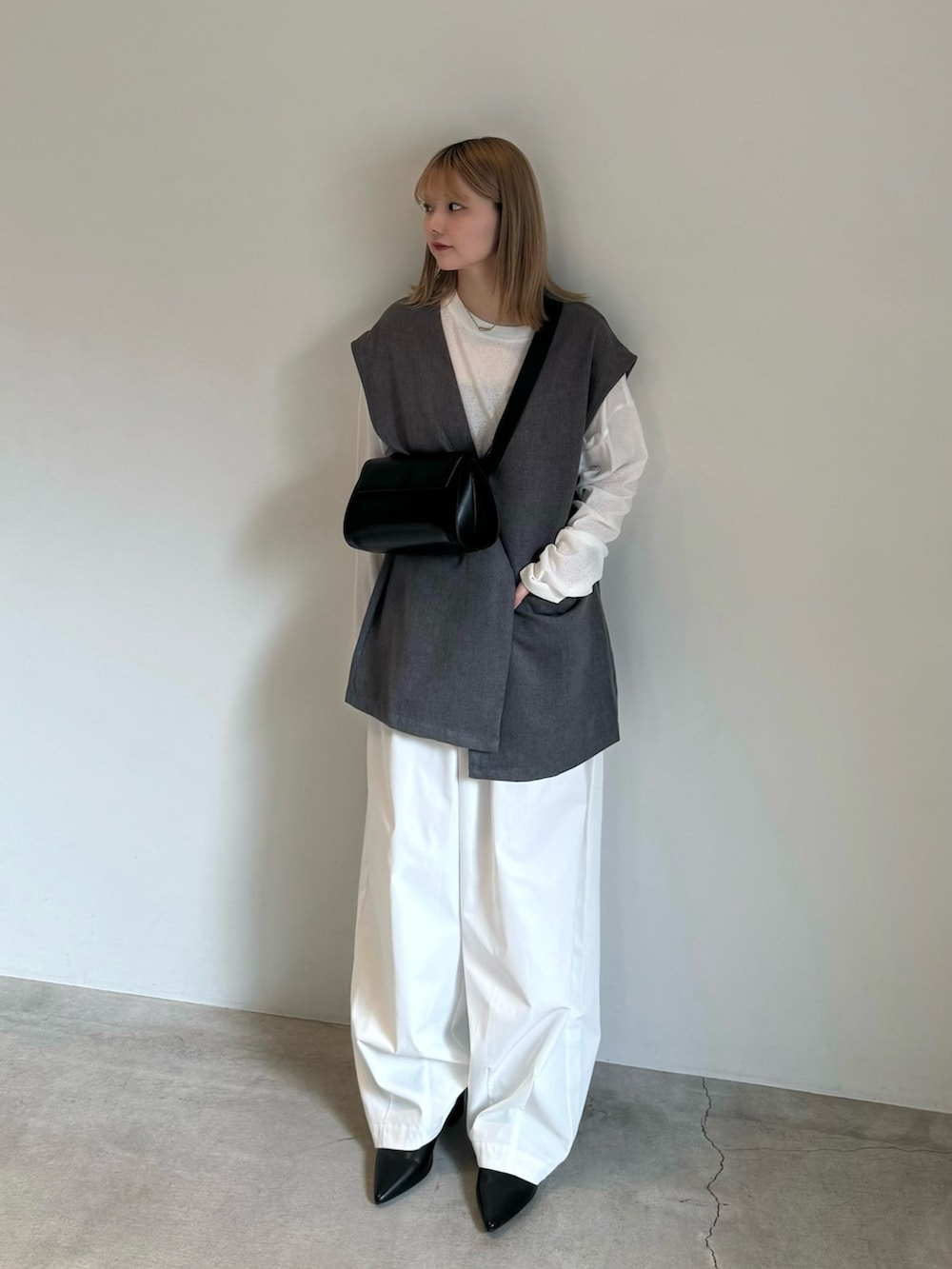 グレー系のベスト、ホワイト系のTシャツ/カットソー、ブラック系のキャミソールを着用したレディースの春コーディネートの2枚目の写真