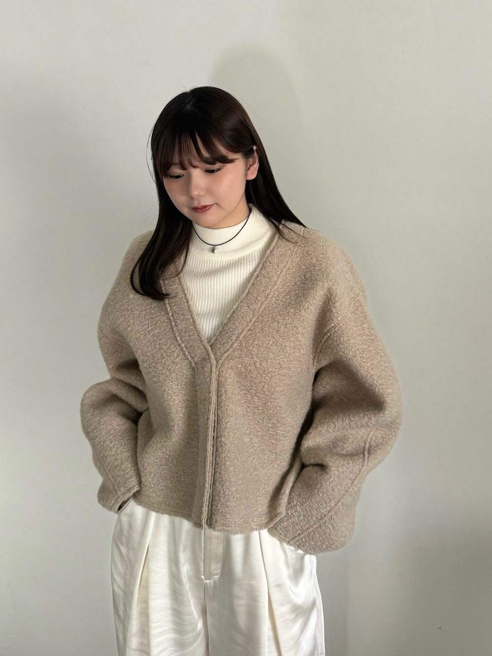 ベージュ系のカーディガン/ボレロ、ホワイト系のニット/セーター、ホワイト系のスラックスを着用したレディースの冬コーディネートの6枚目の写真