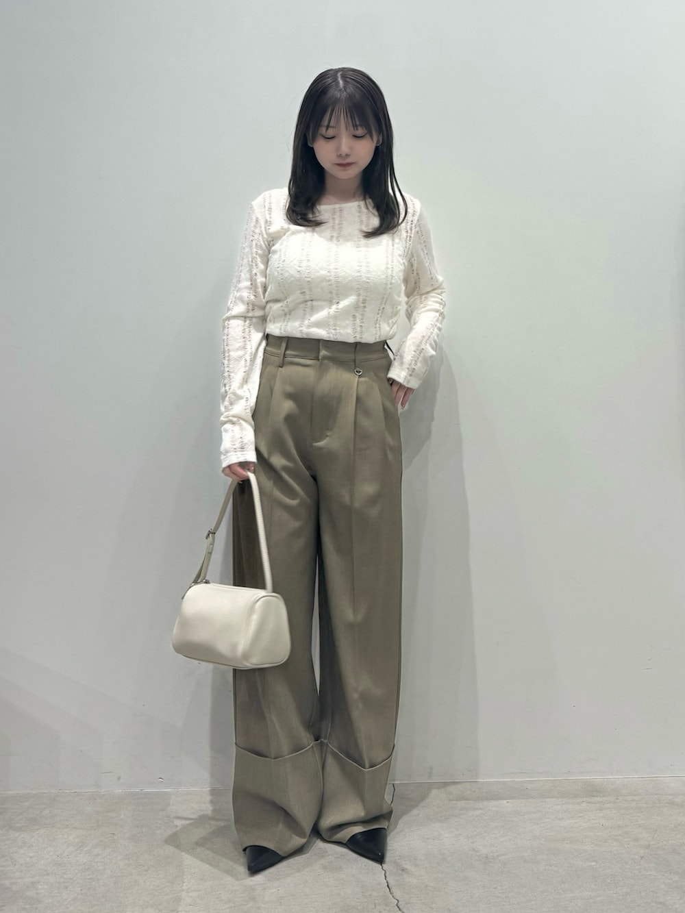 ブラウン系のスラックス、ホワイト系のハンドバッグ、ホワイト系のキャミソールを着用したレディースの春コーディネートの2枚目の写真