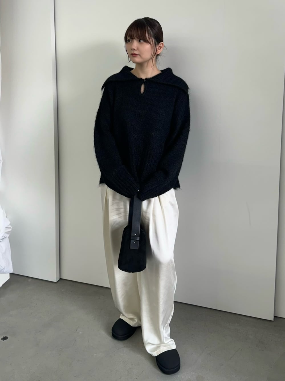 ブラック系のニット/セーター、ホワイト系のスラックス、ブラック系のハンドバッグを着用したレディースの冬コーディネートの2枚目の写真