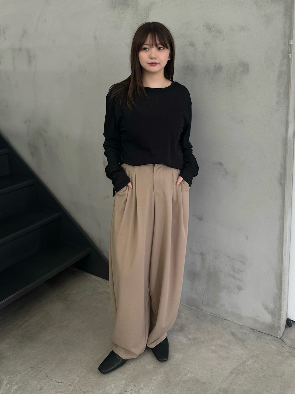 ブラック系のTシャツ/カットソー、ベージュ系のスラックスを着用したレディースの冬コーディネートの2枚目の写真