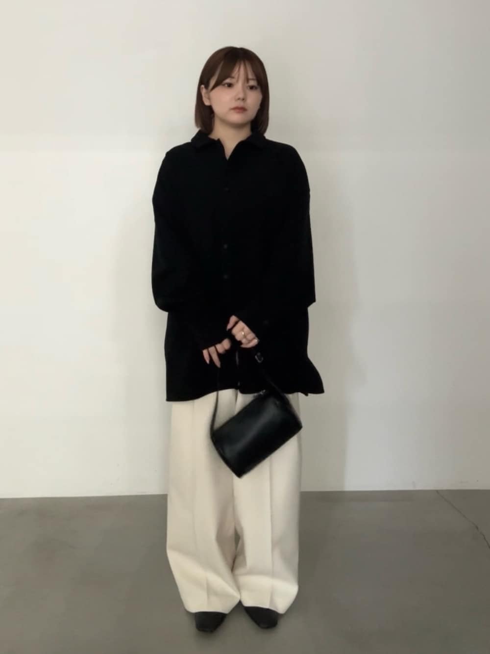 ブラック系のシャツ/ブラウス、ベージュ系のスラックス、ブラック系のハンドバッグを着用したレディースの秋コーディネートの2枚目の写真