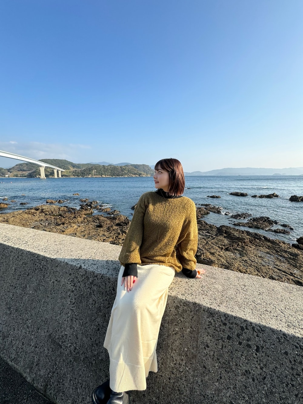 ブラック系のニット/セーター、ホワイト系のスカート、グリーン系のニット/セーターを着用したレディースの夏コーディネートの2枚目の写真