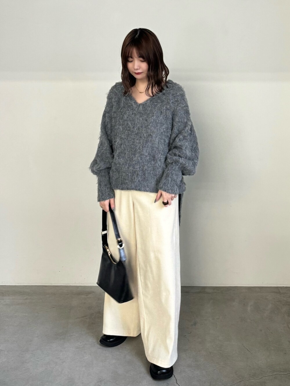 グレー系のニット/セーター、ホワイト系のその他パンツ、ブラック系のハンドバッグを着用したレディースの冬コーディネートの2枚目の写真