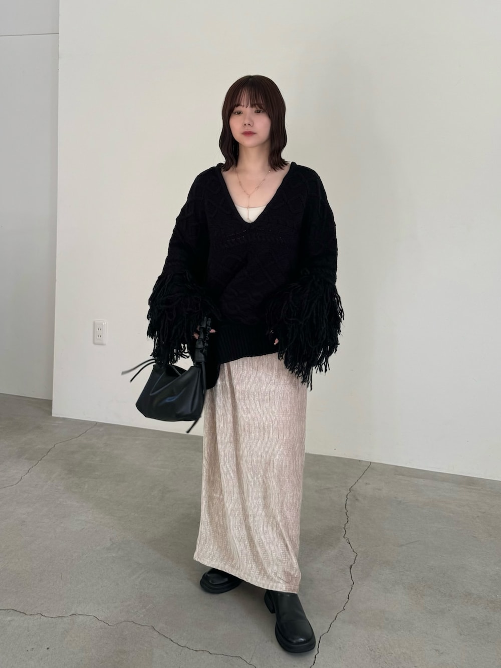 ブラック系のニット/セーター、ベージュ系のスカート、ブラック系のハンドバッグを着用したレディースの秋コーディネートの2枚目の写真