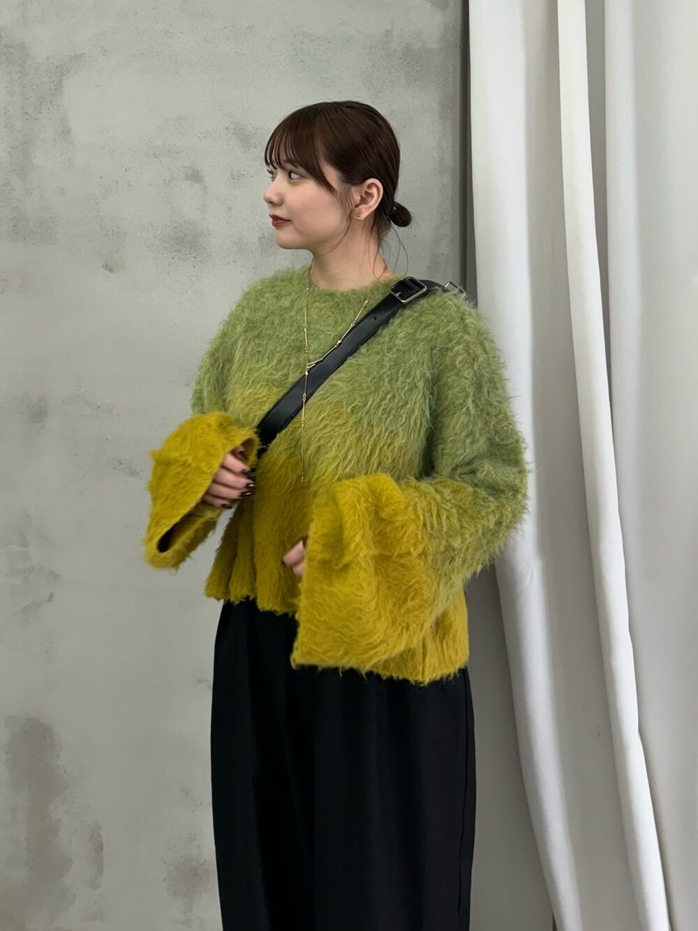 ブラック系のスラックス、イエロー系のニット/セーター、ブラック系のショルダーバッグを着用したレディースの秋コーディネートの2枚目の写真
